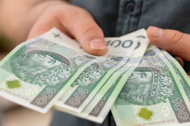 Polskie złotówki w banknotach trzymane w ręce