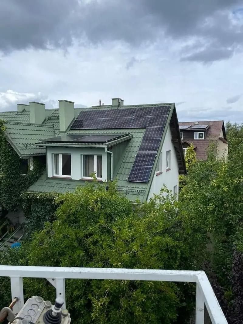 Panele fotowoltaiczne na dachu domu w Polsce o zielonym kolorze dachówki